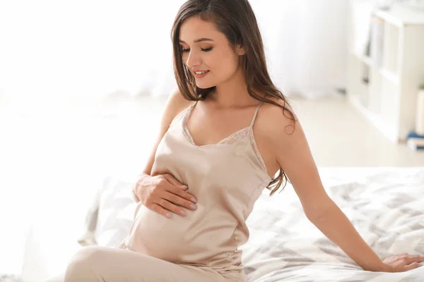 Mooie jonge zwangere vrouw in slaapkamer — Stockfoto