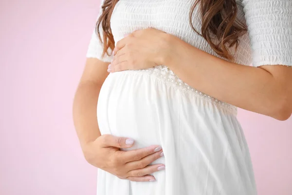 Młoda kobieta w ciąży na kolorowym tle, zbliżenie — Zdjęcie stockowe