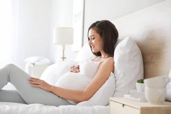 Schöne junge schwangere Frau im Schlafzimmer — Stockfoto