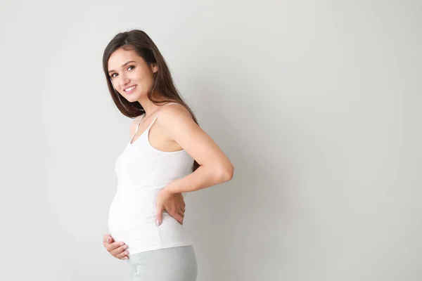Mujer embarazada joven sobre fondo claro — Foto de Stock
