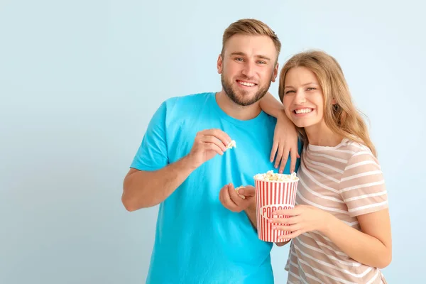 Fiatal pár Popcorn néz filmet a világos háttér — Stock Fotó