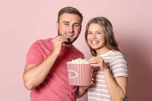 Νεαρό ζευγάρι με ποπκόρν βλέποντας ταινία στο χρώμα φόντο — Φωτογραφία Αρχείου