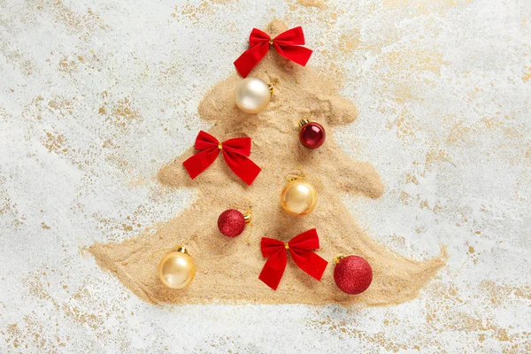 Fir tree made of sand with Christmas decor on light background — Stock Photo, Image