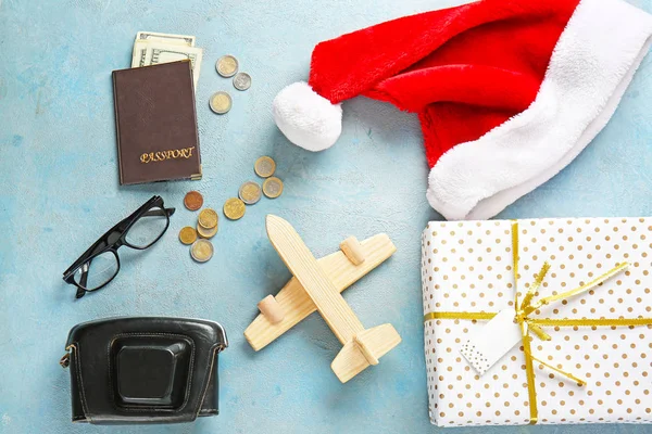 Kompozycja z pudełka na prezenty, kapelusz Świętego Mikołaja, aparat fotograficzny, paszport i pieniądze na kolorowym tle. Świąteczne wakacje — Zdjęcie stockowe