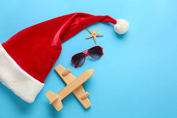 Santa Claus hat with airplane, sunglasses and starfish on color background — Stock Photo, Image