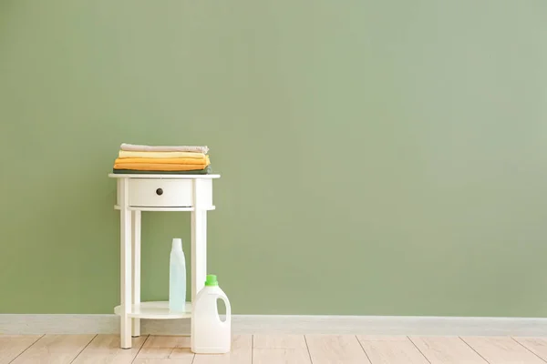 Table with clean towels and washing agents near color wall