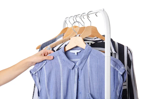 Woman choosing clothes hanging on rack against white background — Stock Photo, Image