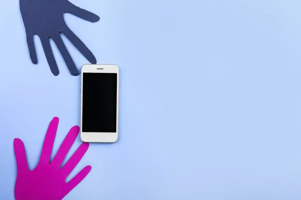 Modern mobile phone with paper human palms on color background — Stock Photo, Image