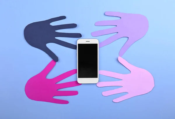 Modern mobile phone with paper human palms on color background