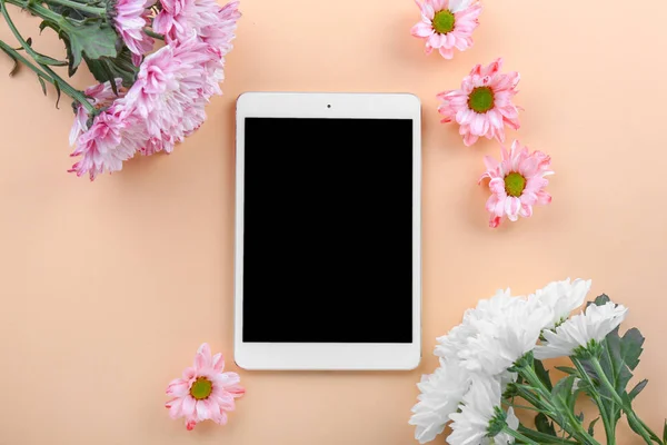 Modern tablet computer with flowers on color background