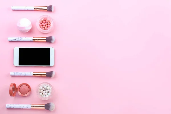 Modern mobile phone with makeup brushes and cosmetics on color background — Stock Photo, Image