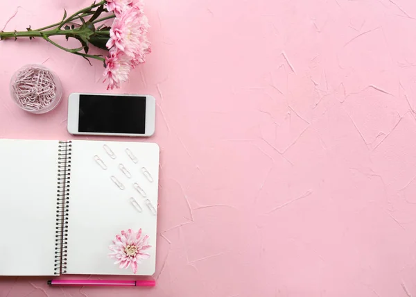 Moderne mobiele telefoon met bloemen en briefpapier op kleur achtergrond — Stockfoto