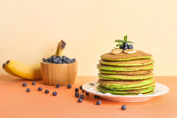 Crêpes vertes savoureuses avec banane et myrtille sur fond de couleur — Photo