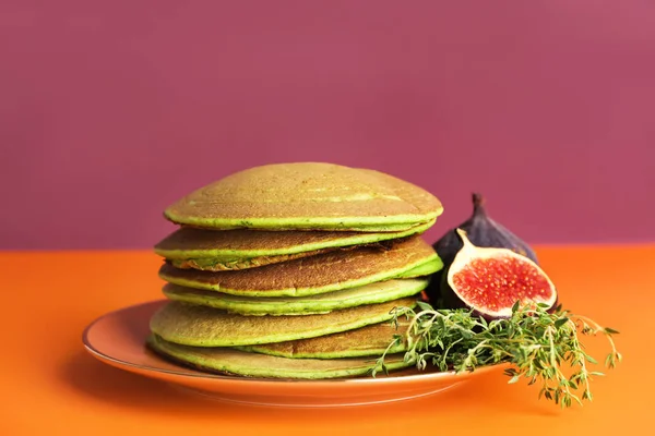 Вкусные зеленые блины с фруктами инжира на цветном фоне — стоковое фото