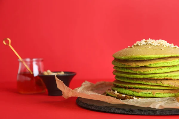 Вкусные зеленые блины с медом и орехами на цветном фоне — стоковое фото