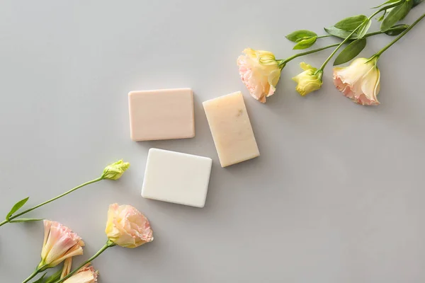 Different soap with flowers on grey background — Stock Photo, Image