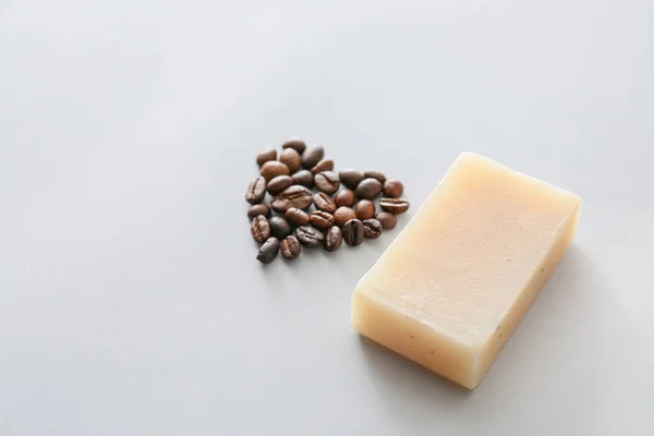 Soap with heart shape made of coffee beans on grey background — Stock Photo, Image