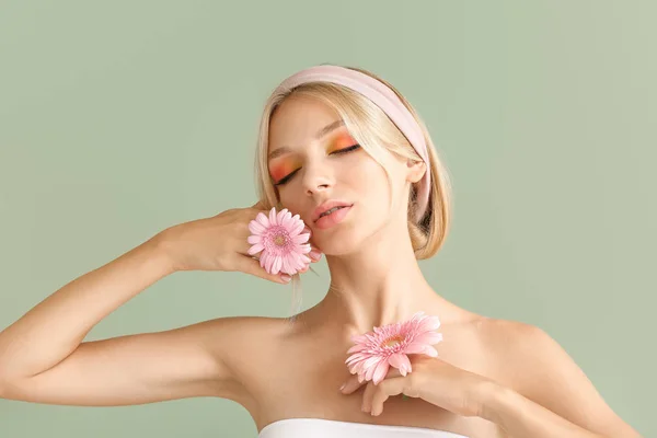 Hermosa mujer joven con flores de gerberas en el fondo de color — Foto de Stock
