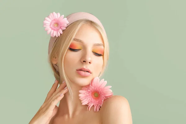 Schöne junge Frau mit Gerbera-Blumen auf farbigem Hintergrund — Stockfoto