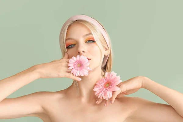 Hermosa mujer joven con flores de gerberas en el fondo de color — Foto de Stock