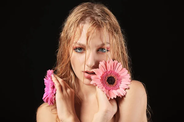 Beautiful sexy young woman with gerbera flowers on dark background — Stock Photo, Image