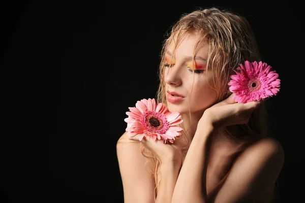 Beautiful sexy young woman with gerbera flowers on dark background — Stock Photo, Image