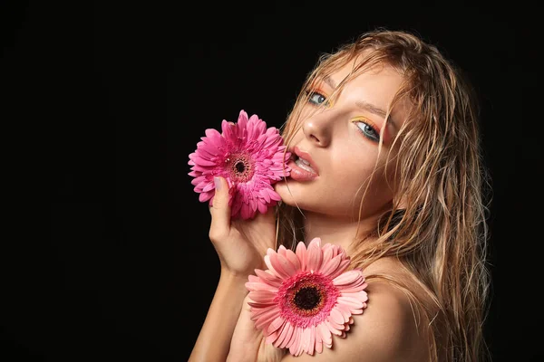 Piękna seksowna młoda kobieta z kwiatami Gerbera na ciemnym tle — Zdjęcie stockowe