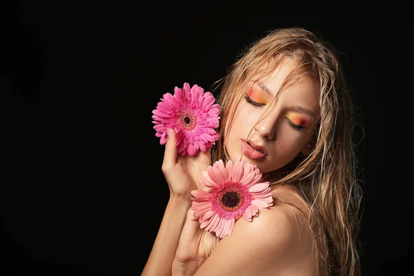 Piękna seksowna młoda kobieta z kwiatami Gerbera na ciemnym tle — Zdjęcie stockowe
