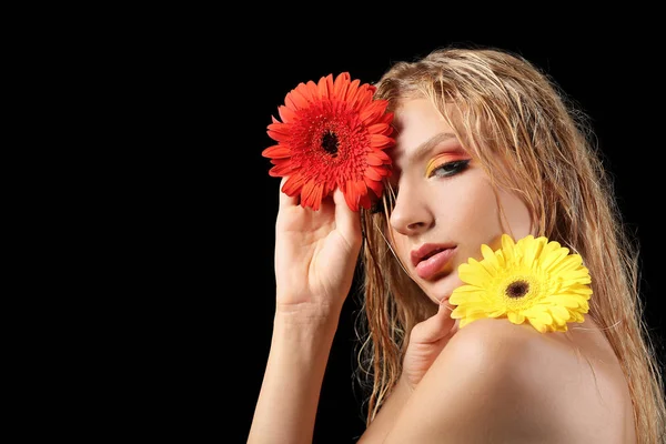 Bella giovane donna sexy con fiori gerbera su sfondo scuro — Foto Stock