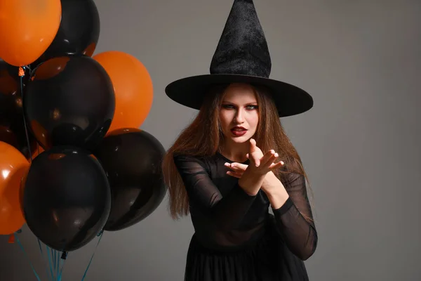 Hermosa mujer vestida de bruja para Halloween sobre fondo gris —  Fotos de Stock