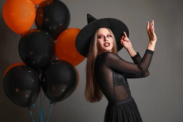 Hermosa mujer vestida de bruja para Halloween sobre fondo gris —  Fotos de Stock