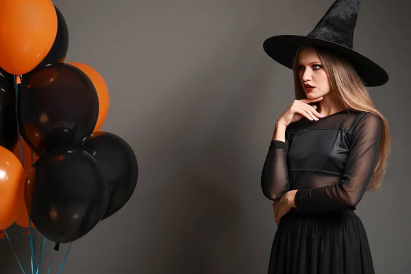 Mulher bonita vestida como bruxa para o Halloween em fundo cinza — Fotografia de Stock