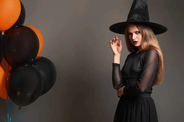 Красивая женщина, одетая как ведьма на Хэллоуин на сером фоне — стоковое фото