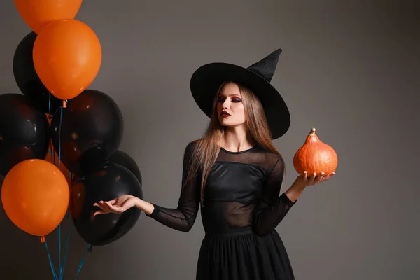 Beautiful woman dressed as witch for Halloween on grey background — Stock Photo, Image