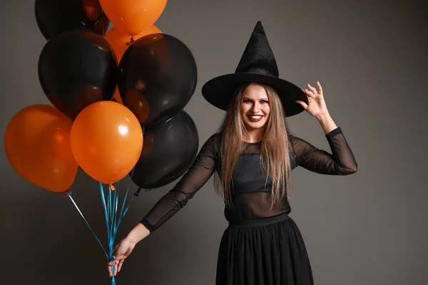 Mulher bonita vestida como bruxa para o Halloween em fundo cinza — Fotografia de Stock