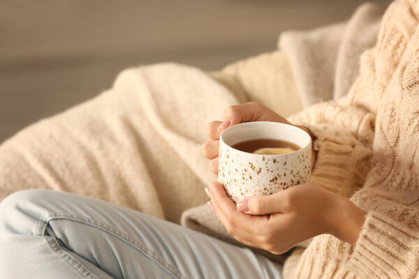 Молодая женщина пьет горячий чай дома, крупным планом
