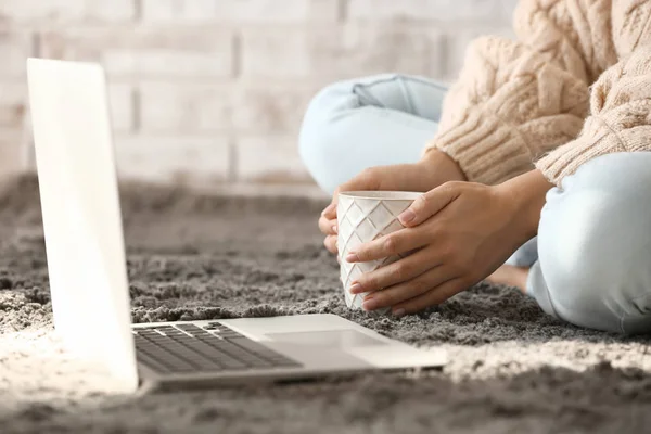 Młoda kobieta z laptopem picie gorącej herbaty w domu — Zdjęcie stockowe