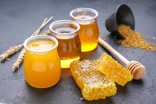 Potten van zoete honing en kammen op tafel — Stockfoto