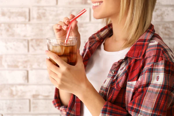 Woman with glass of cold cola near brick wall — Stock Photo, Image