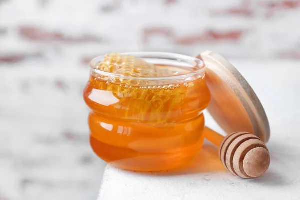 Burk med söt honung och skopa på bordet — Stockfoto