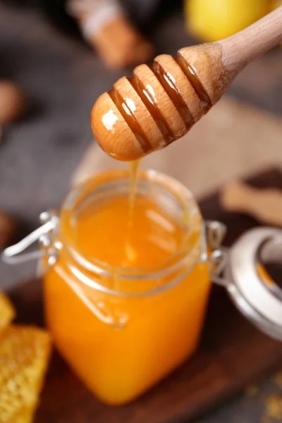Honig aus dem Löffel ins Glas auf den Tisch gießen — Stockfoto
