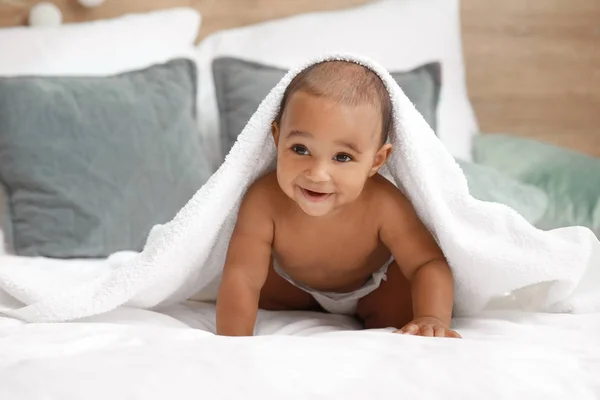 Bebê afro-americano bonito com toalha macia na cama em casa — Fotografia de Stock