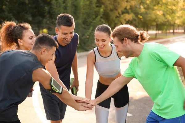 Group of sporty young people putting hands together outdoors — Stock Photo, Image