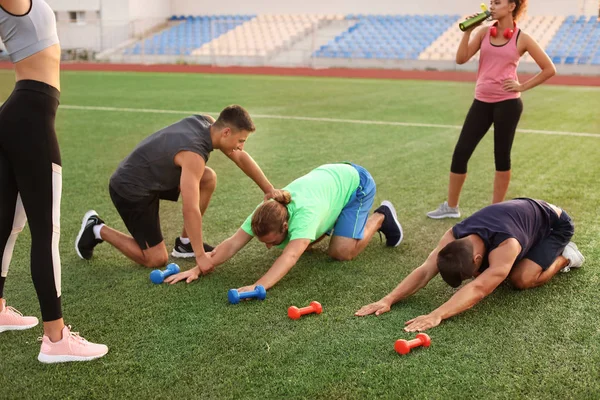 Skupina sportovně vyškolení mladých lidí s trenérem na stadionu — Stock fotografie