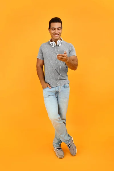 Hombre afroamericano guapo con teléfono móvil y auriculares en el fondo de color —  Fotos de Stock