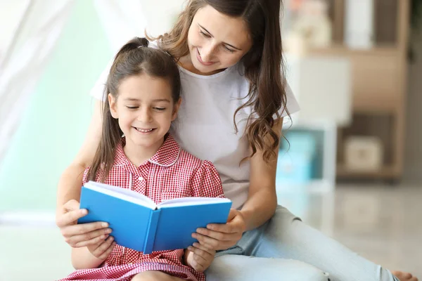 Cute little girl and her elder sister reading book at home — Stock Image Cute little girl and her elder sister reading book at home Stock Photo