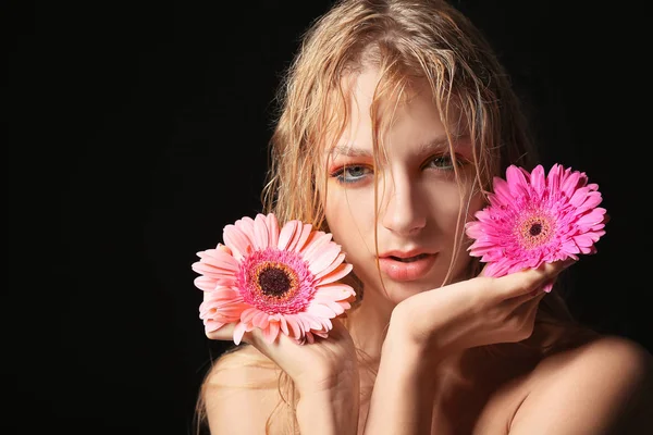 Beautiful sexy young woman with gerbera flowers on dark background — Stock Photo, Image