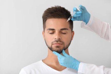 Yakışıklı adam gri arka plan üzerinde dolgu enjeksiyonu alan