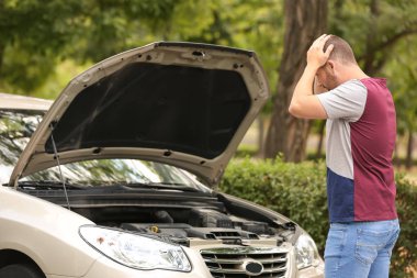 Yolda kırık arabanın yanında duran adam sigorta acentesini arıyor.