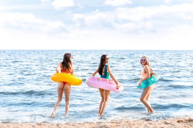 Kumsalda yüzme yüzükleri olan güzel genç kadınlar.